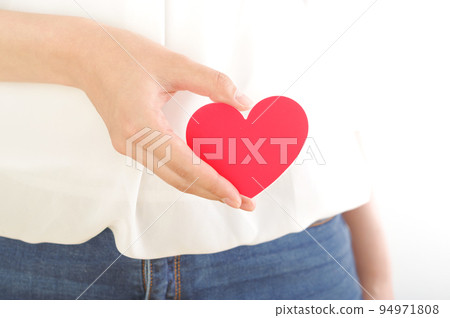 A woman with a heart mark in front of her stomach A woman with a heart mark in front of her stomach 94971808