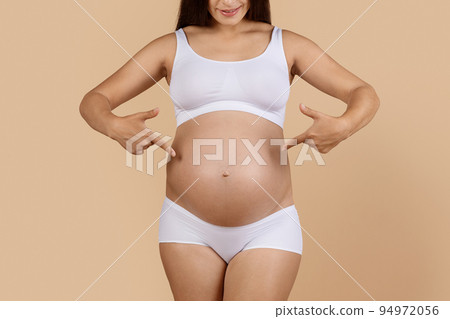 Happy Awaiting. Young Pregnant Woman In White Underwear Pointing At Her Belly Happy Awaiting. Young Pregnant Woman In White Underwear Pointing At Her Belly 94972056