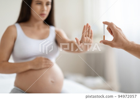 Pregnant woman showing stop gesture to cigarette Pregnant woman showing stop gesture to cigarette 94972057