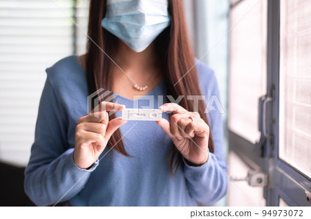 Asian woman patient holding positive test result for coronavirus or covid 19 at home 94973072