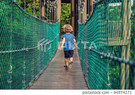 The boy is running on a suspension bridge in Kuala Lumpur, Malaysia 94974271