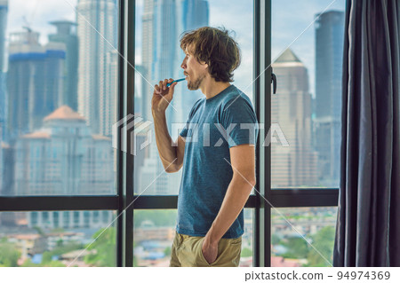 Young man brushing his teeth in his bathroom Young man brushing his teeth in his bathroom 94974369