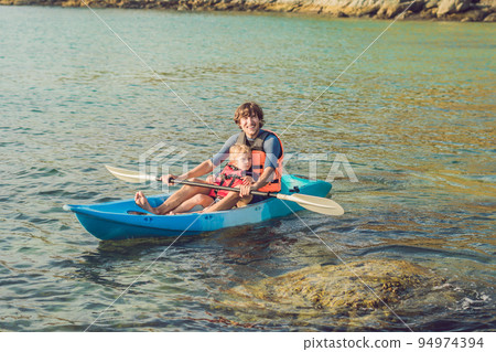 Father and son kayaking at tropical ocean. Father and son kayaking at tropical ocean. 94974394