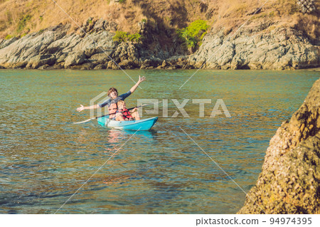 Father and son kayaking at tropical ocean. Father and son kayaking at tropical ocean. 94974395