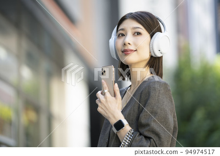 戴著耳機和拿著智能手機的年輕女人 94974517