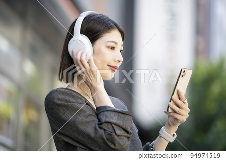 Young woman wearing headphones looking at smartphone screen 94974519