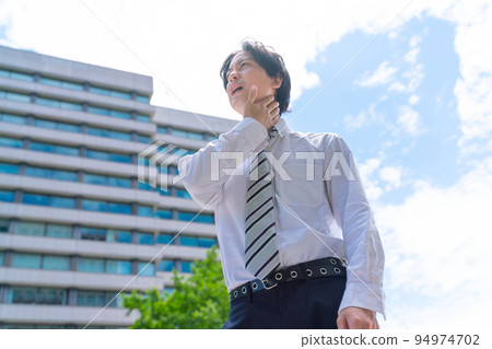 A businessman suffering from the heat wave 94974702