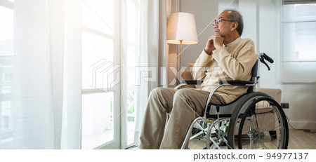 Asian senior man disabled sitting alone in wheelchair looking through window at hospital Asian senior man disabled sitting alone in wheelchair looking through window at hospital 94977137