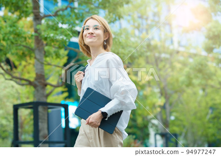 A woman walking in a green office district 94977247