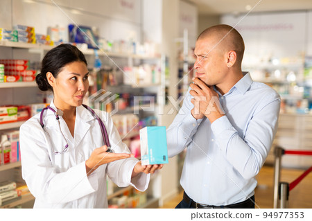 Man asks to help pharmacist choose medicine for toothache Man asks to help pharmacist choose medicine for toothache 94977353
