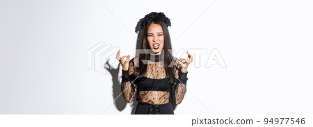 Image of woman in halloween costume looking like angry evil witch, cursing and clenching fists mad. Female in black dress and wreath trick or treating, standing white background Image of woman in halloween costume looking like angry evil witch, cursing and clenching fists mad. Female in black dress and wreath trick or treating, standing white background 94977546