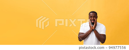Young Stressed man with hand on his face showing sadness and despair. Isolated over yellow background. 94977556
