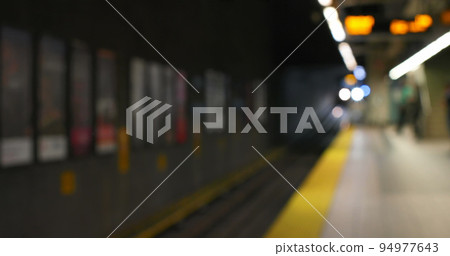 Image of defocussed signs and lighting on the platform of an underground metro station at night 94977643