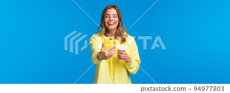 Cheerful smiling blond caucasian female blogger record video or take selfie on her smartphone, laughing and grinning as holding take-away cup of coffee, stand blue background Cheerful smiling blond caucasian female blogger record video or take selfie on her smartphone, laughing and grinning as holding take-away cup of coffee, stand blue background 94977803