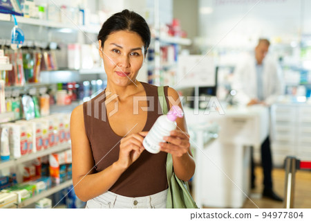 Female customer looking for products of body care in pharmacy closeup Female customer looking for products of body care in pharmacy closeup 94977804