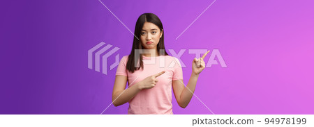 Moody upset whining girlfriend unhappy pointing left, sulking look miserable and distressed, express regret and disappointment, complain bad fortune, stand purple background displeased 94978199