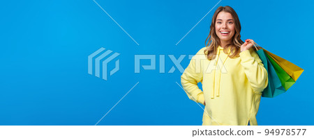 Shopping time. Girl relaxing after hard working days buying things in store on weekend, hold bags on back and smiling relieved, release stress through purchasing clothes, blue background 94978577
