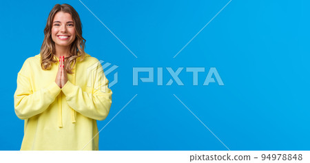 Cheerful young european female practice yoga, greeting sensei with namaste gesture, hold hands in pray and smiling grateful with relaxed carefree expression, smiling camera, blue background 94978848