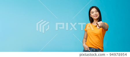 Lucky winner. Cheerful charismatic asian cute urban girl stand yellow t-shirt smiling friendly pointing finger camera choosing, picking person, inviting you team, stand happy blue background 94978954