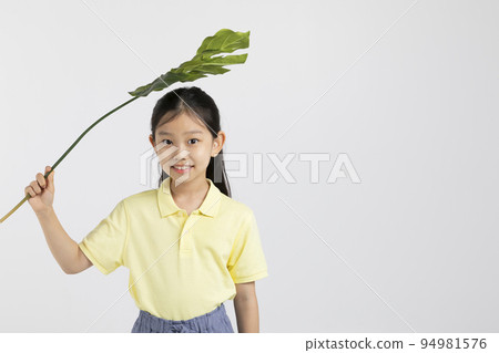 Korean young girl wearing gym clothes in white background studio__holding tropical leaves Korean young girl wearing gym clothes in white background studio__holding tropical leaves 94981576
