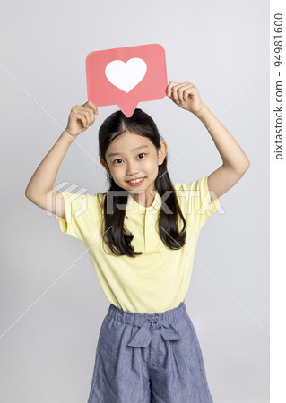 Korean young girl wearing gym clothes in white background studio__holding a heart shape copyspace panel 94981600