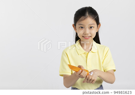 Korean young girl wearing gym clothes in white background studio__squeeze sun cream on the hand 94981623
