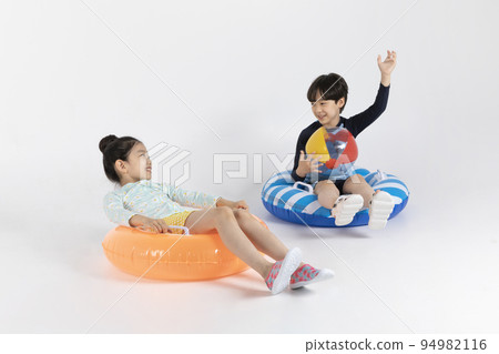 Korean boy and girl, summer concept in white background_ sitting on a inflatable pool float and playing around Korean boy and girl, summer concept in white background_ sitting on a inflatable pool float and playing around 94982116