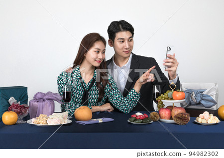 Korean young couple, man and woman wearing modern Hanbok_watching smartphone Korean young couple, man and woman wearing modern Hanbok_watching smartphone 94982302