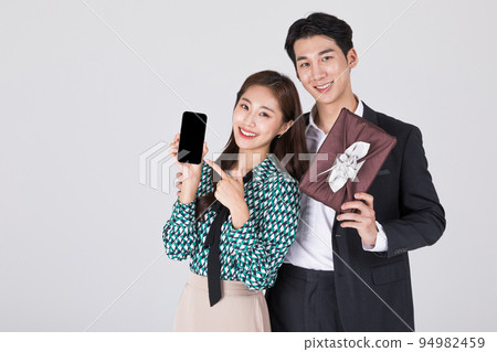 Korean young couple, man and woman wearing modern Hanbok_holding gift box and smartphone 94982459