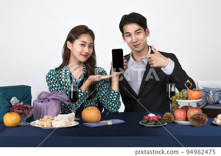 Korean young couple, man and woman wearing modern Hanbok_showing smartphone Korean young couple, man and woman wearing modern Hanbok_showing smartphone 94982475