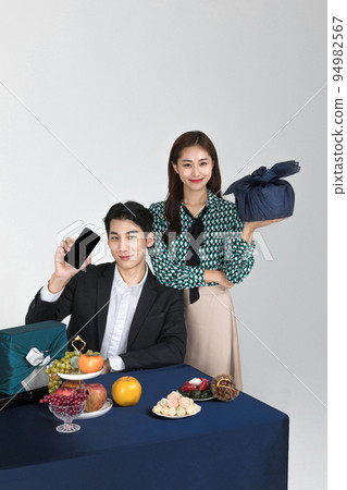Korean young couple, man and woman wearing modern Hanbok_holding gift box and smartphone 94982567