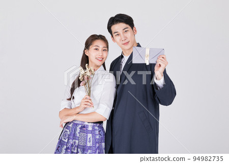 Korean couple_young man and woman in 20s_wearing modern Hanbok_holding flower and Korean traditional wedding clutch, envelope Korean couple_young man and woman in 20s_wearing modern Hanbok_holding flower and Korean traditional wedding clutch, envelope 94982735