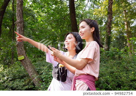 two Korean Asian female friends in 20s hiking and plogging in mountain__path finding using smartphone two Korean Asian female friends in 20s hiking and plogging in mountain__path finding using smartphone 94982754