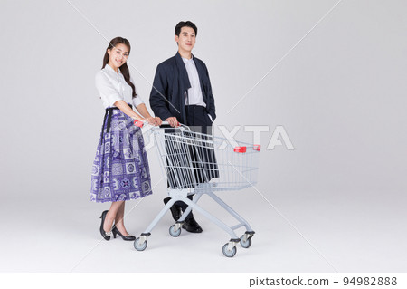Korean couple_young man and woman in 20s_wearing modern Hanbok_with shopping cart Korean couple_young man and woman in 20s_wearing modern Hanbok_with shopping cart 94982888
