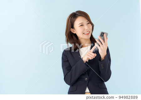 A woman in a suit holding a smartphone A woman in a suit holding a smartphone 94982889
