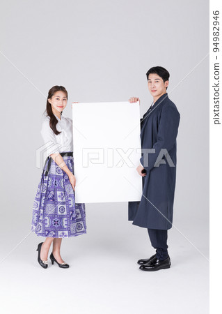 Korean couple_young man and woman in 20s_wearing modern Hanbok_holding copyspace panel Korean couple_young man and woman in 20s_wearing modern Hanbok_holding copyspace panel 94982946