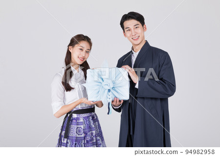 Korean couple_young man and woman in 20s_wearing modern Hanbok_holding traditional box Korean couple_young man and woman in 20s_wearing modern Hanbok_holding traditional box 94982958