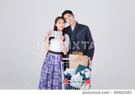 Korean couple_young man and woman in 20s_wearing modern Hanbok_with shopping cart Korean couple_young man and woman in 20s_wearing modern Hanbok_with shopping cart 94982985