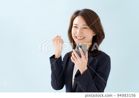 A woman in a suit holding a smartphone 94983156