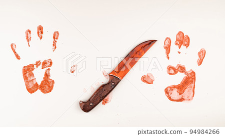 Bloody knife and hand prints in blood on a white table.  94984266