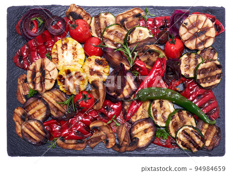 Grilled vegetables mix on a stone serving board - zucchini eggplant onions corn mushroom tomato 94984659