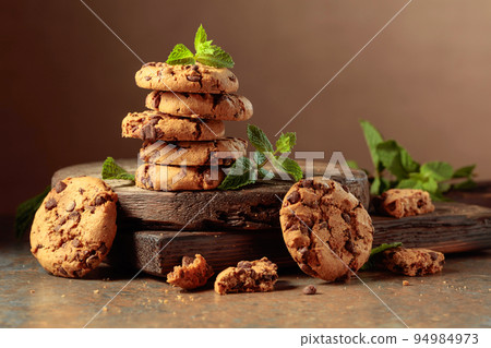 Chocolate cookies with mint on a rustic brown background. Chocolate cookies with mint on a rustic brown background. 94984973