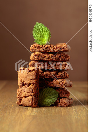 Brownie with mint on a wooden table. Brownie with mint on a wooden table. 94984976