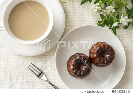 白盤上的法式糕點卡內萊和拿鐵咖啡 94985230