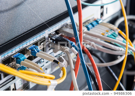 Fiber Optic cables connected to an optic ports - data switch in internet data center 94986306