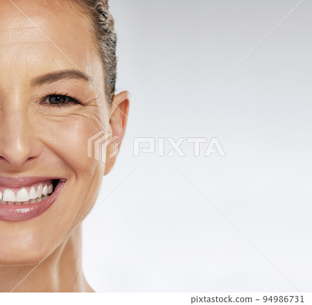 Half face, skincare and mature woman with smile for facial wellness in retirement against grey mockup studio background. Elderly model with beauty and skin health from dermatology with mock up space 94986731