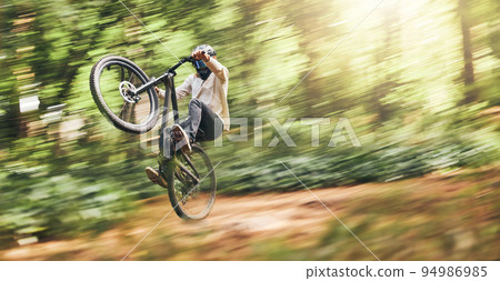 Motion blur of mountain bike man, action jump and bicycle speed adventure, freedom and fast race in woods. Cycling sports athlete training, moving and energy in forest, nature and outdoor competition 94986985