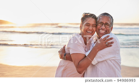 Senior couple, beach travel and hug by water of Dubai, happy on holiday for retirement and love by ocean. Portrait of elderly African man and woman hugging by sea during vacation with mockup space 94986993