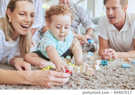 Big family in living room with baby play with toys and fun together on floor on a weekend. Happy grandparents, mother and father with boy for development in their family home sitting on the ground Big family in living room with baby play with toys and fun together on floor on a weekend. Happy grandparents, mother and father with boy for development in their family home sitting on the ground 94987017