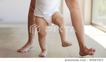Baby, learning and walking with a child taking its first steps with his mother to learn to walk at home. Feet, legs and balance with a kid stepping forward for growth and development in the house Baby, learning and walking with a child taking its first steps with his mother to learn to walk at home. Feet, legs and balance with a kid stepping forward for growth and development in the house 94987853